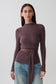 Woman wearing a brown wrap knit long sleeve top.