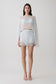 Woman wearing light blue bralette with chiffon cape with matching lace and satin mini skirt.