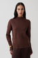 Woman wearing a brown ribbed high neck jumper.