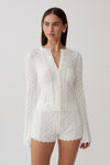 Woman wearing a white pointelle knit long sleeve top with matching shorts.