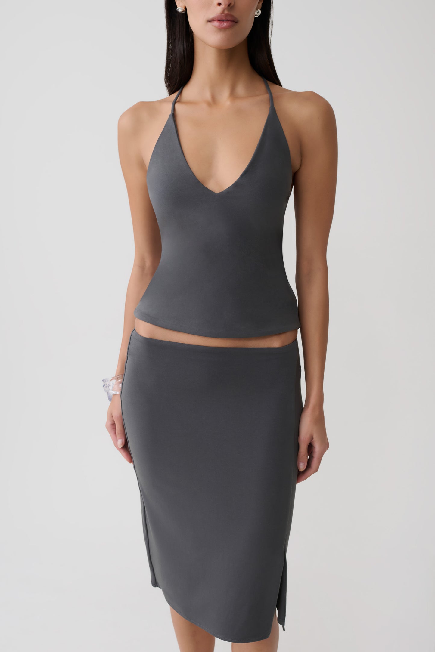 Woman wearing a grey peached jersey draped back top with mini skirt.