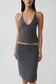 Woman wearing a grey peached jersey draped back top with mini skirt.