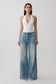 Woman wearing a white slinky halter bodysuit paired with jeans.