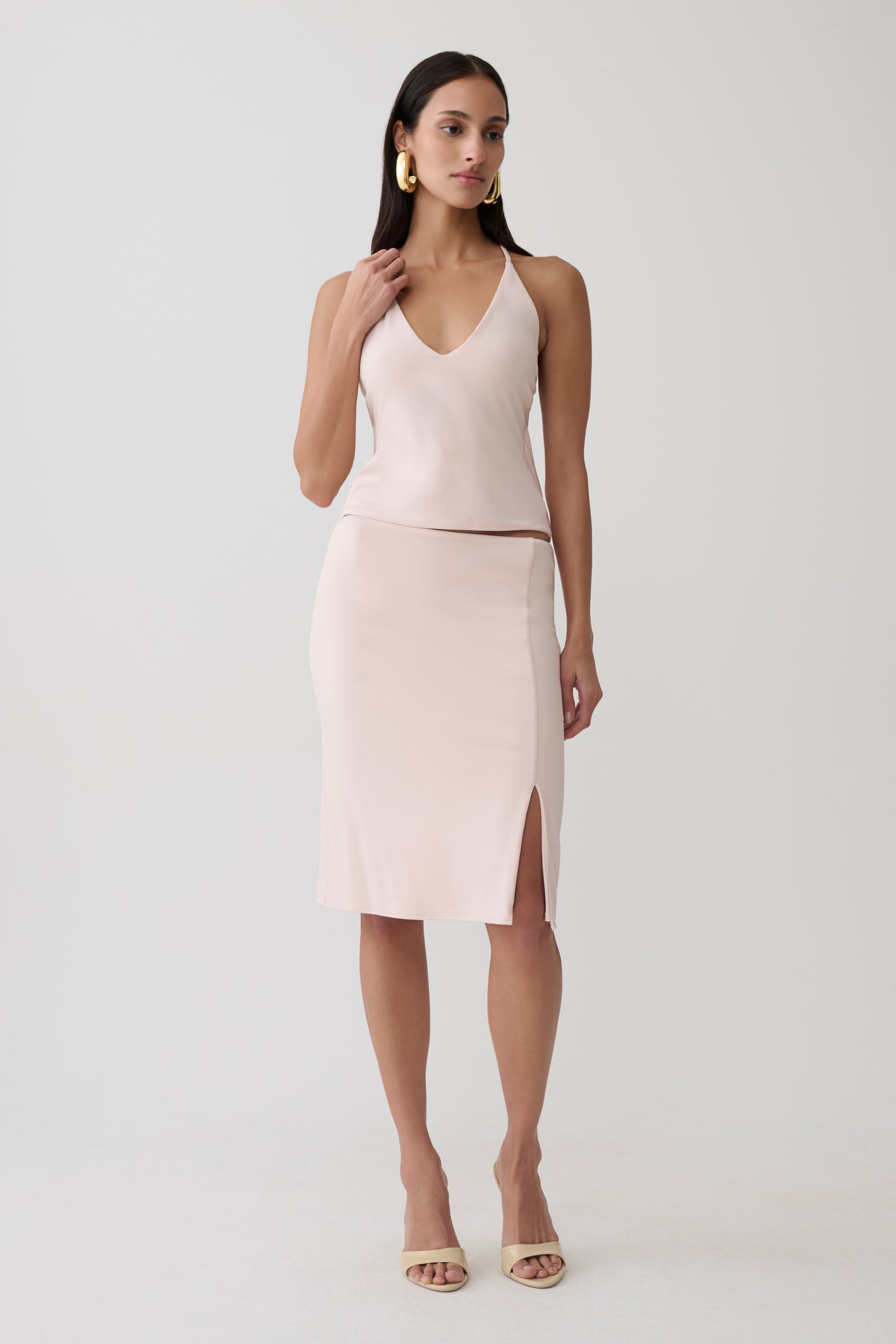 Woman wearing a pink peached jersey draped back top with mini skirt.
