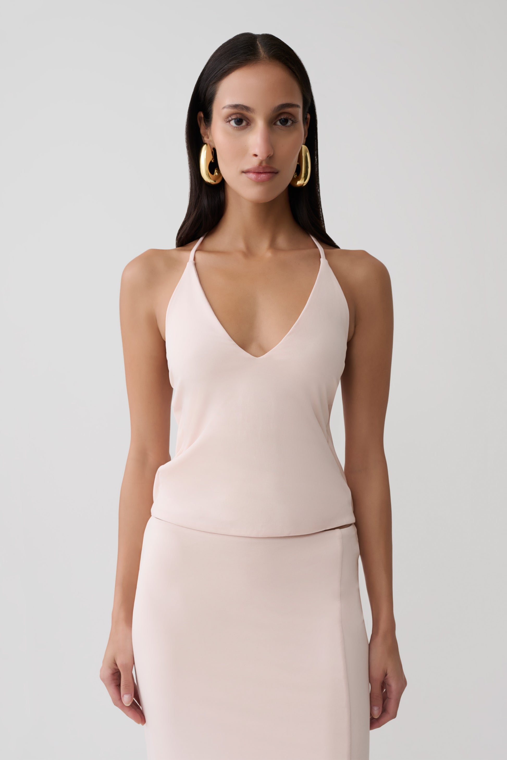 Woman wearing a pink peached jersey draped back top.