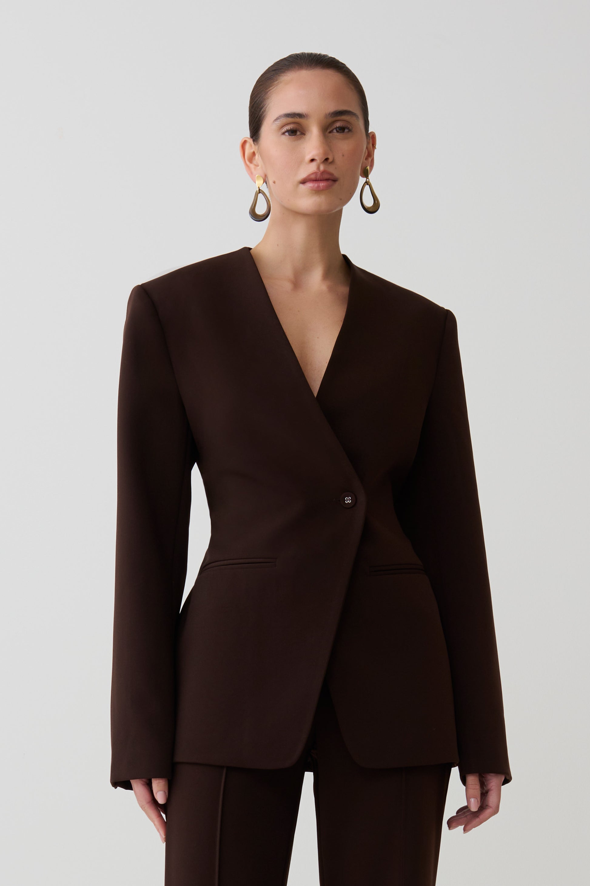 Woman wearing dark brown drop shoulder suiting blazer.
