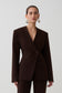 Woman wearing dark brown drop shoulder suiting blazer.