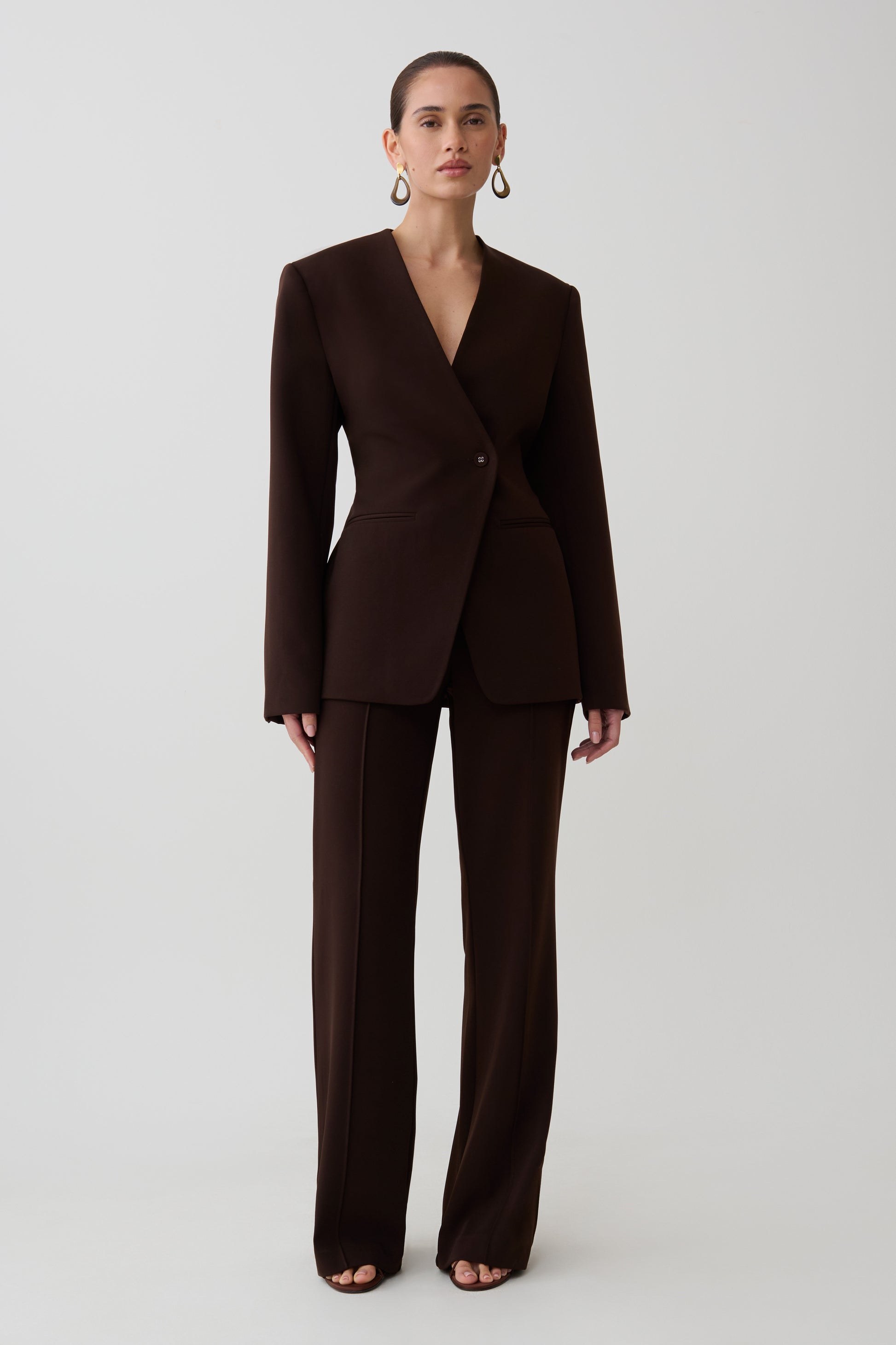 Woman wearing dark brown drop shoulder suiting blazer, with matching suiting pants.