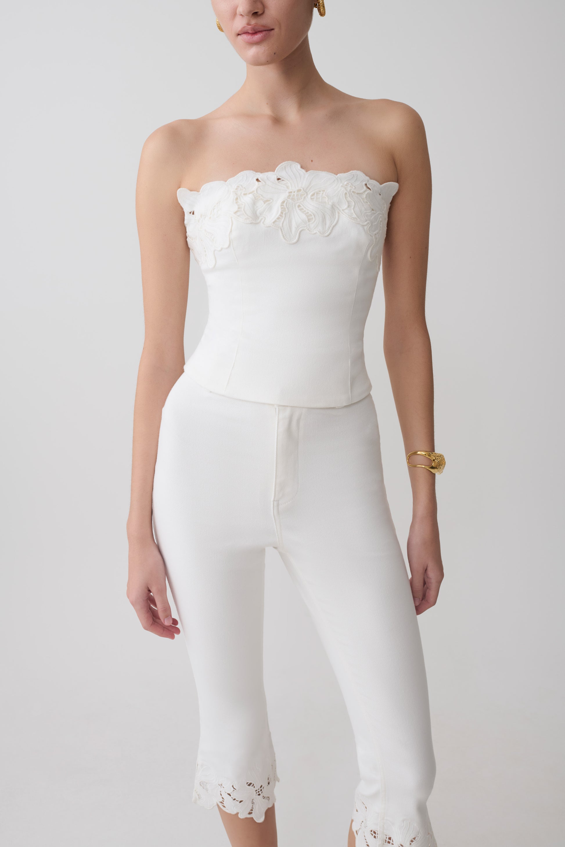 Woman wearing a white embroidery strapless denim top.