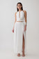 Woman wearing a white halter neck top with hardware and a matching bubble hem midi skirt.
