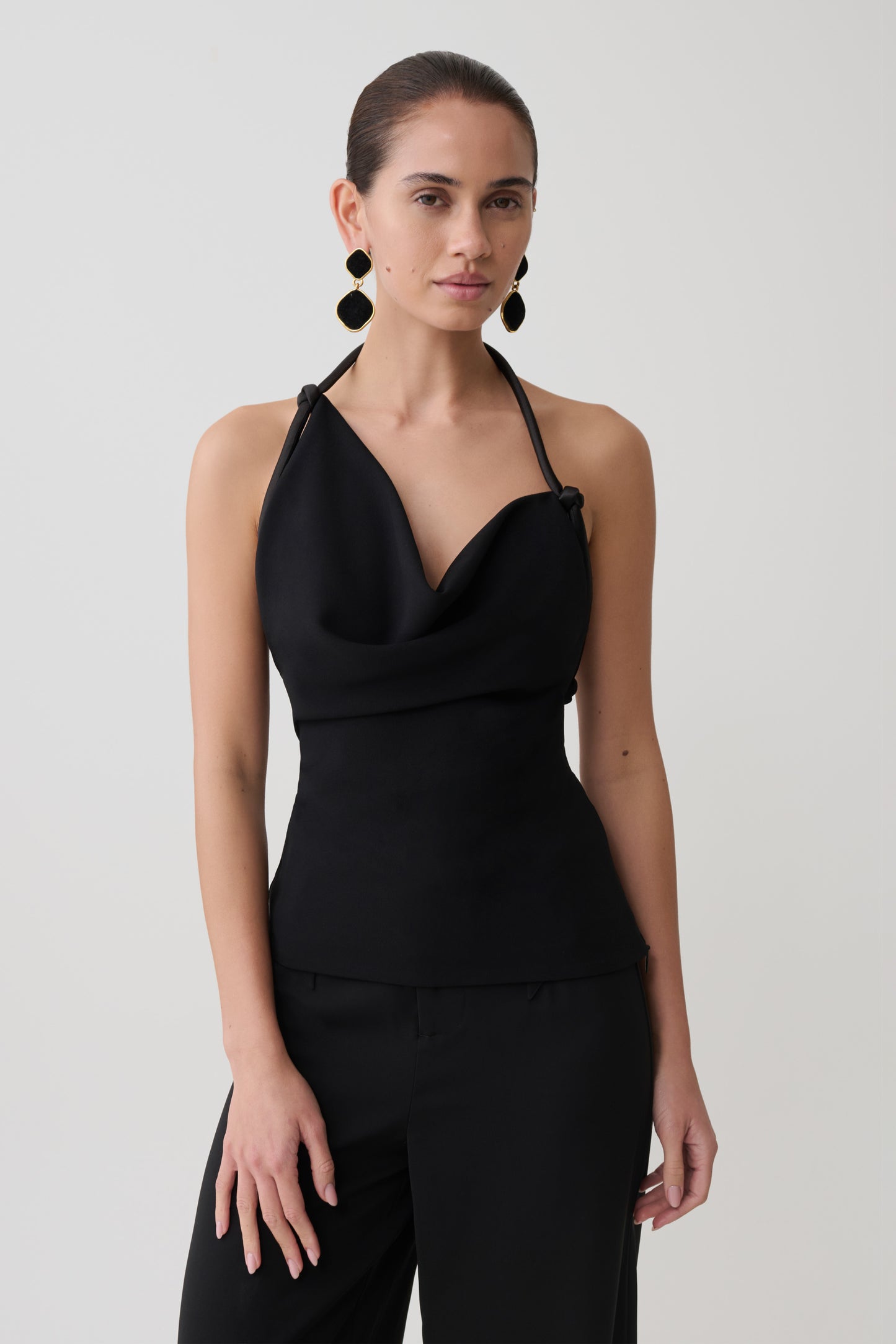 Woman wearing a black halter neck asymmetrical top.