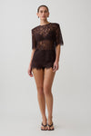 Woman wearing  dark brown shoulder pad short sleeve lace top with matching mini shorts.