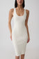 A woman modeling a fitted sleeveless bodycon dress in a warm off-white or cream color, shown from the lips down against a plain light gray studio background.