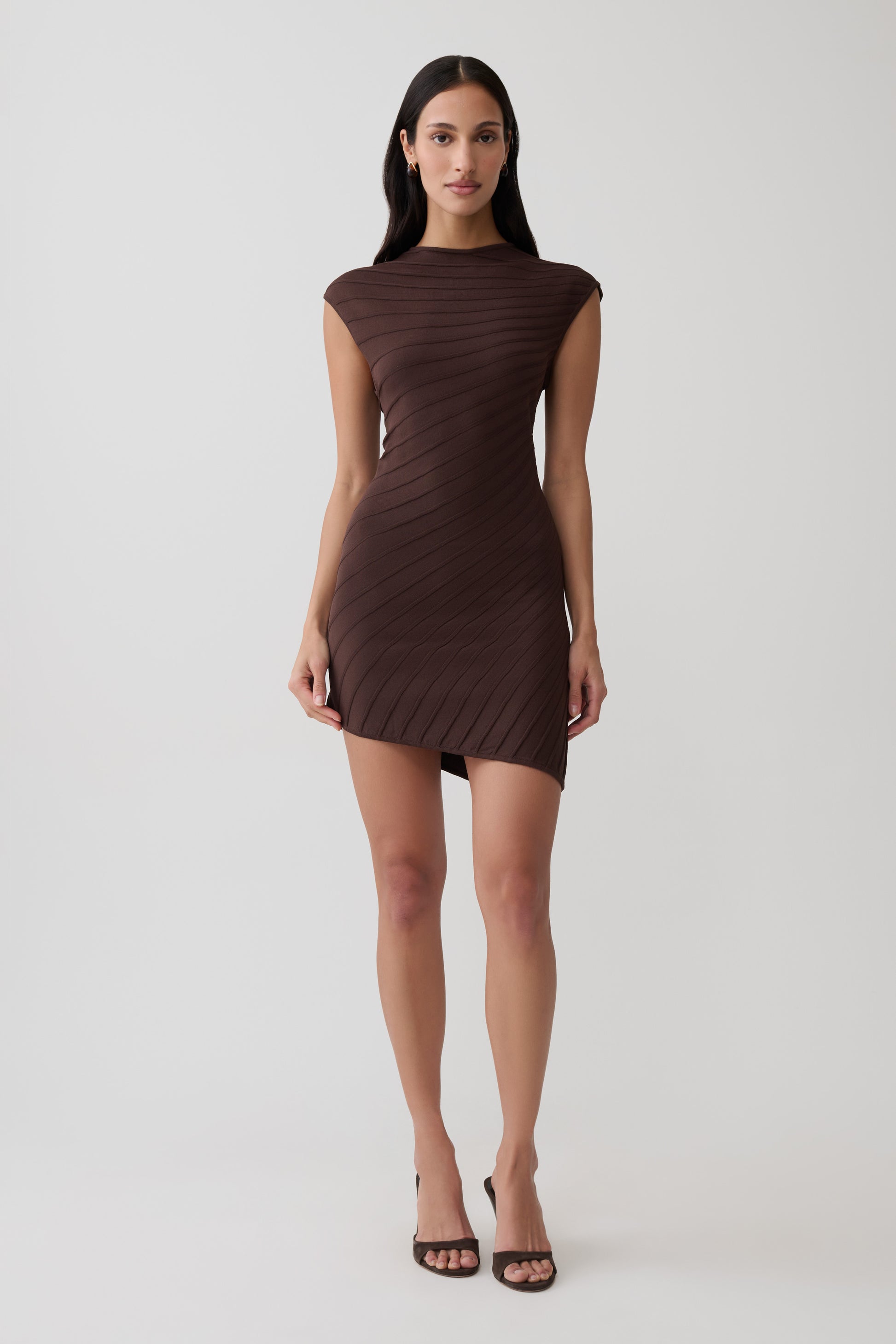 Woman wearing a brown ribbed sleeveless mini dress.