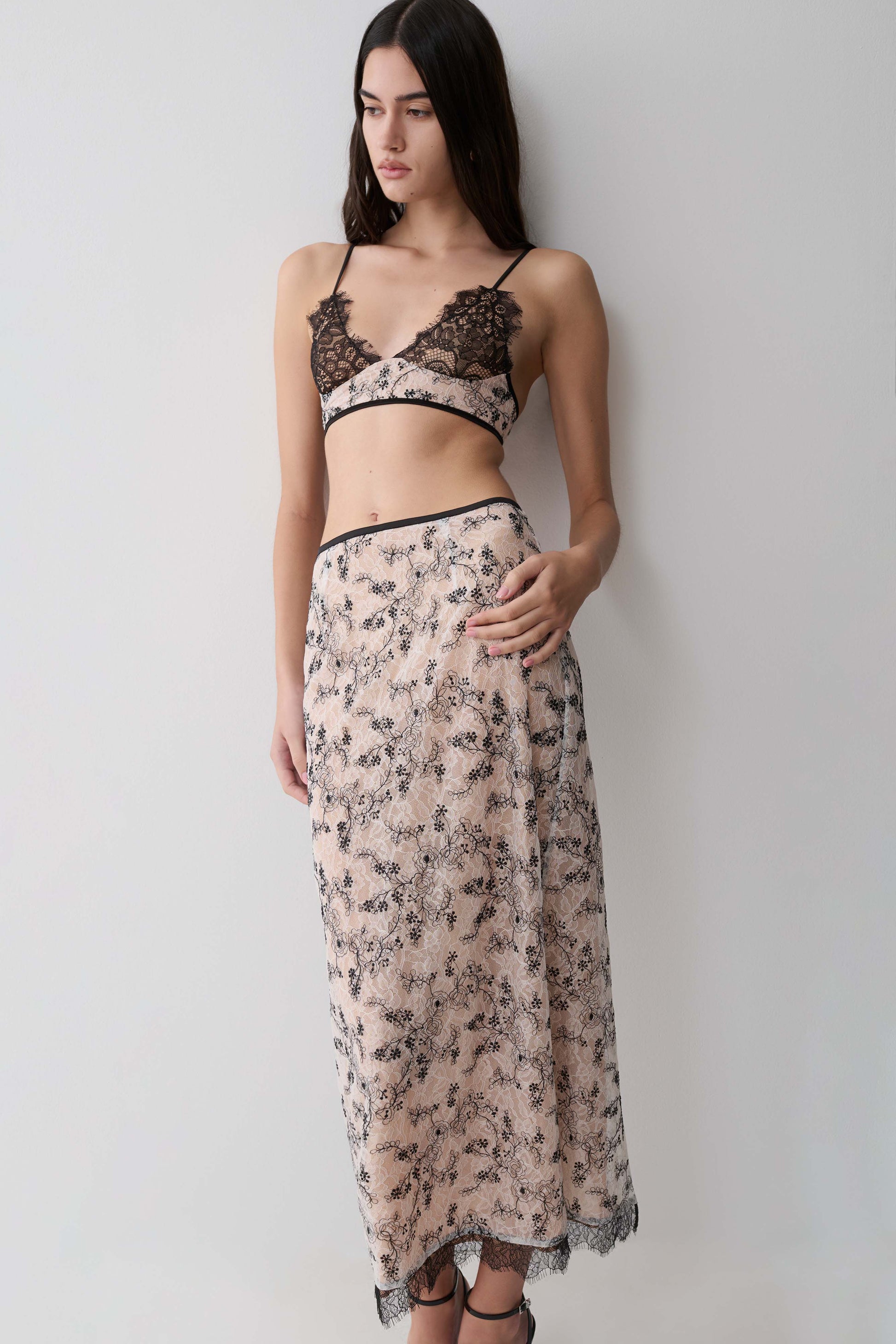 Woman wearing a a nude lace pencil midi skirt.
