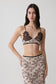 Woman wearing a nude lace sleeveless crop top.