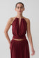 Woman wearing a dark red halter neck top with hardware.