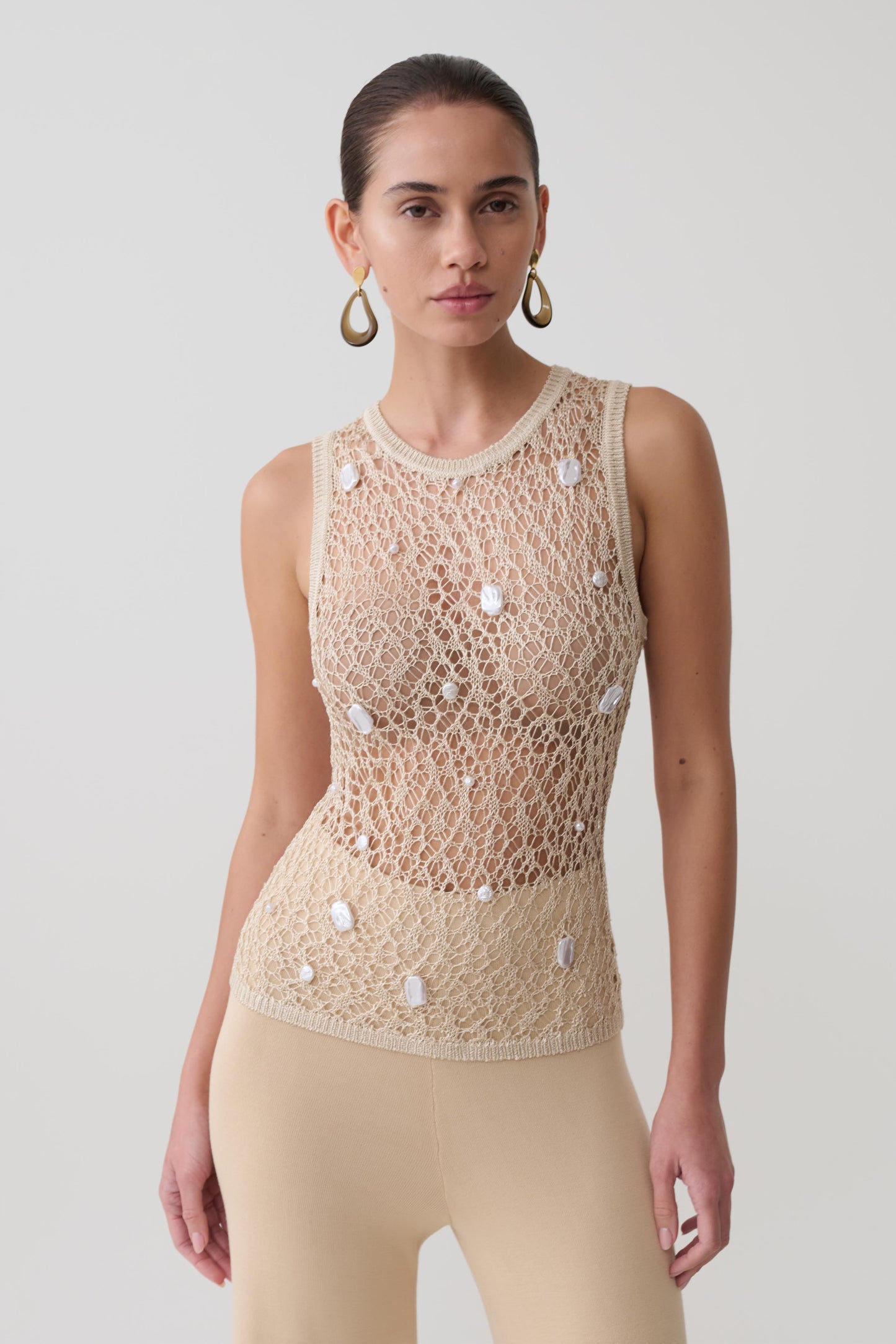 Woman wearing a beige pearl beaded top.