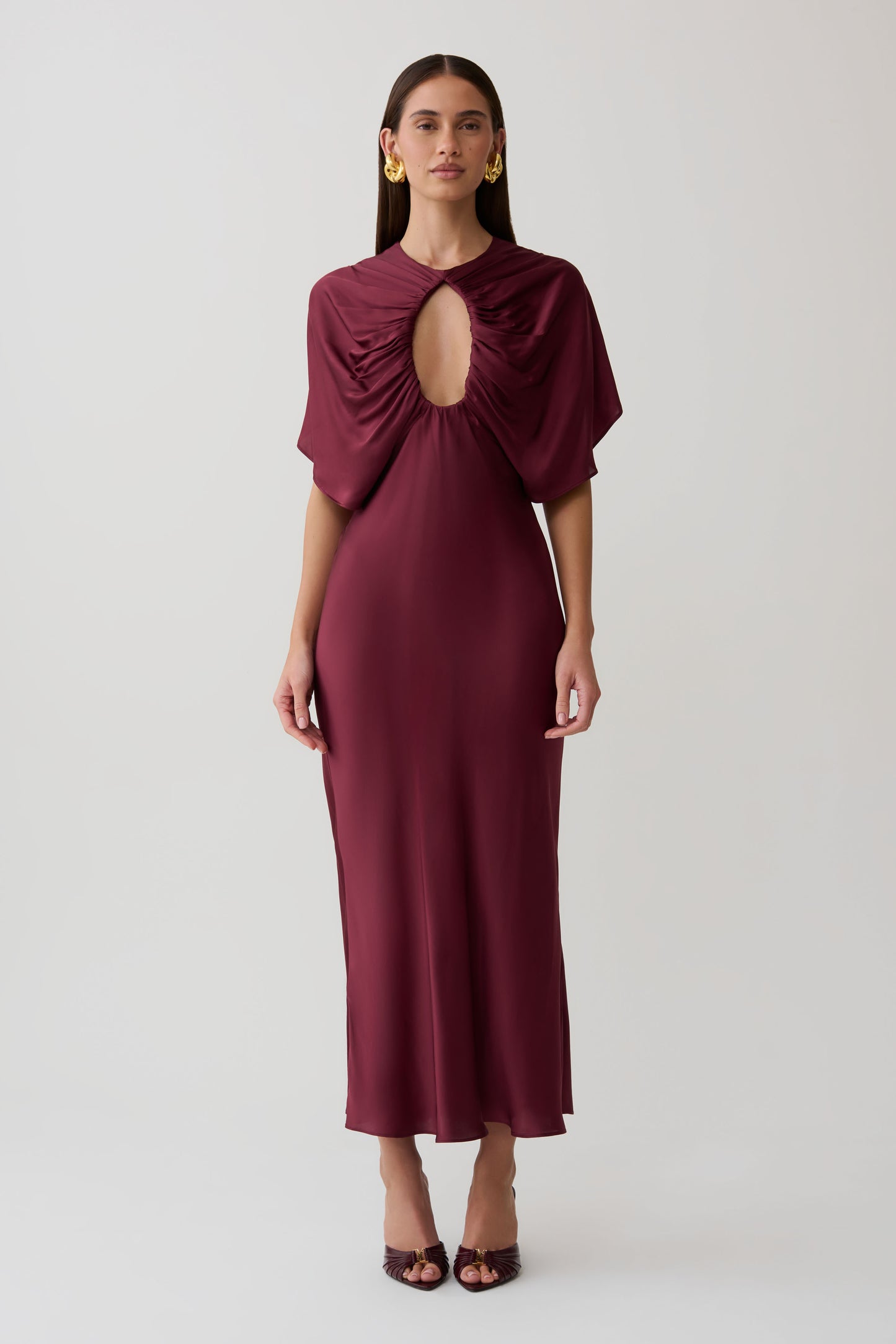 Woman wearing a burgundy cut out satin midi dress.