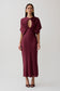 Woman wearing a burgundy cut out satin midi dress.