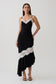 Woman wearing a black and white frilled hem lace midi dress.