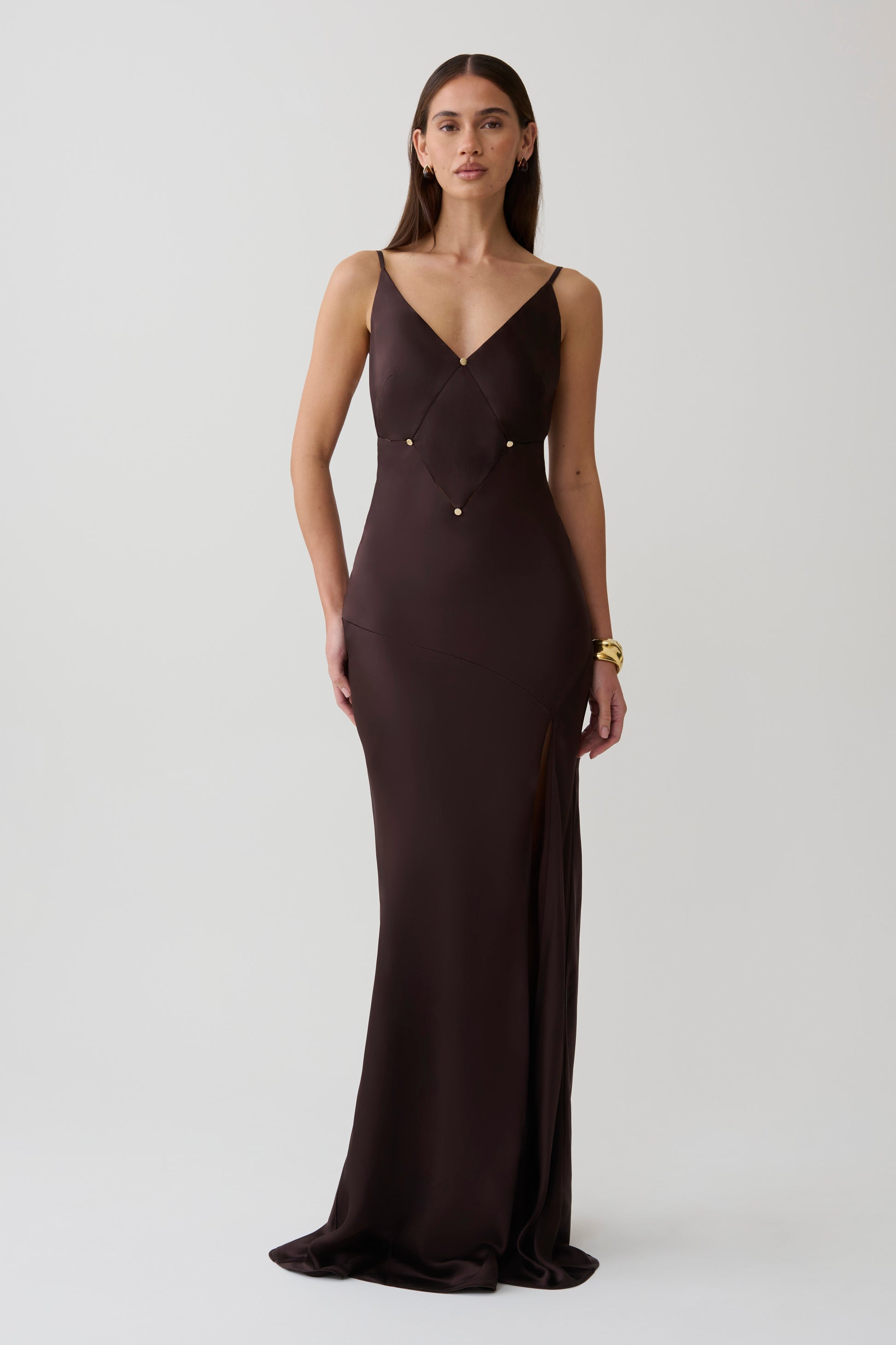 Woman wearing a dark brown v neck satin maxi dress.