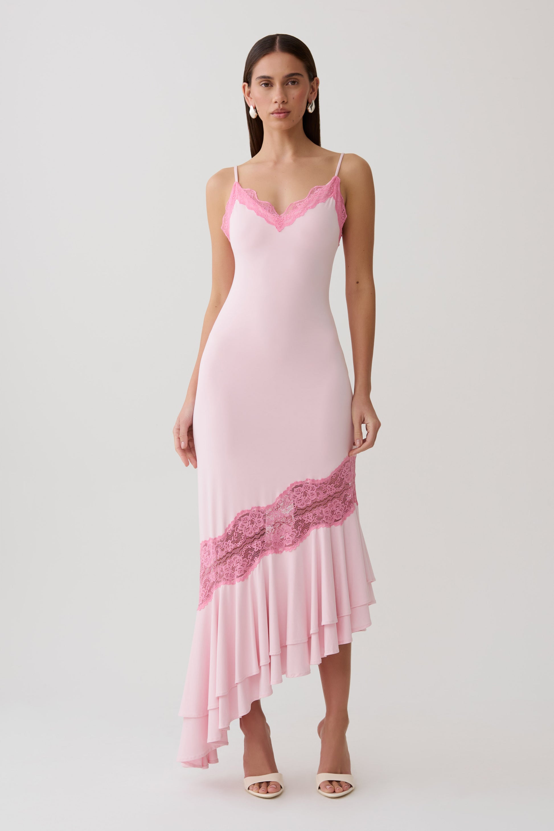 Woman wearing a pink frilled hem lace midi dress.