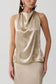Woman wearing a gold satin halter top.