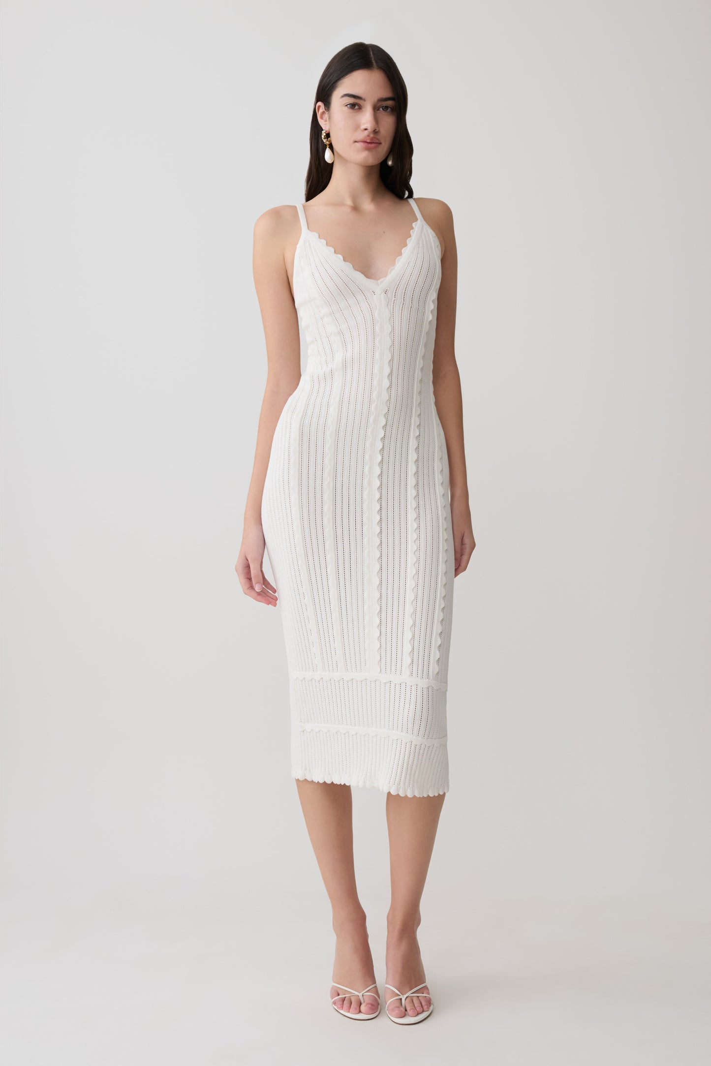 Woman wearing a white scalloped neckline pointelle midi dress.