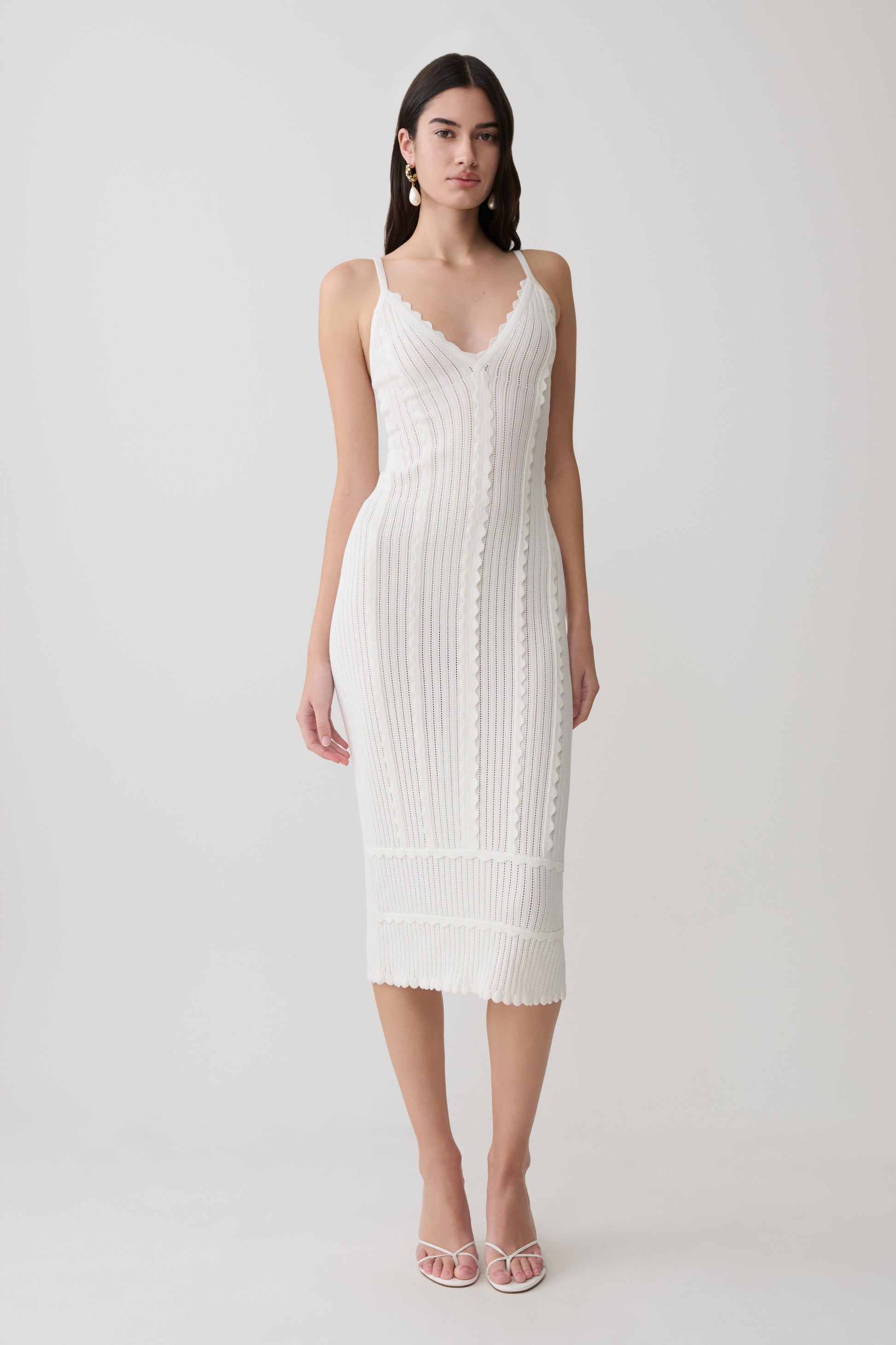 Woman wearing a white scalloped neckline pointelle midi dress.