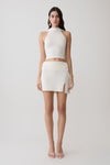 Woman wearing a white halter backless knit top with matching skirt.