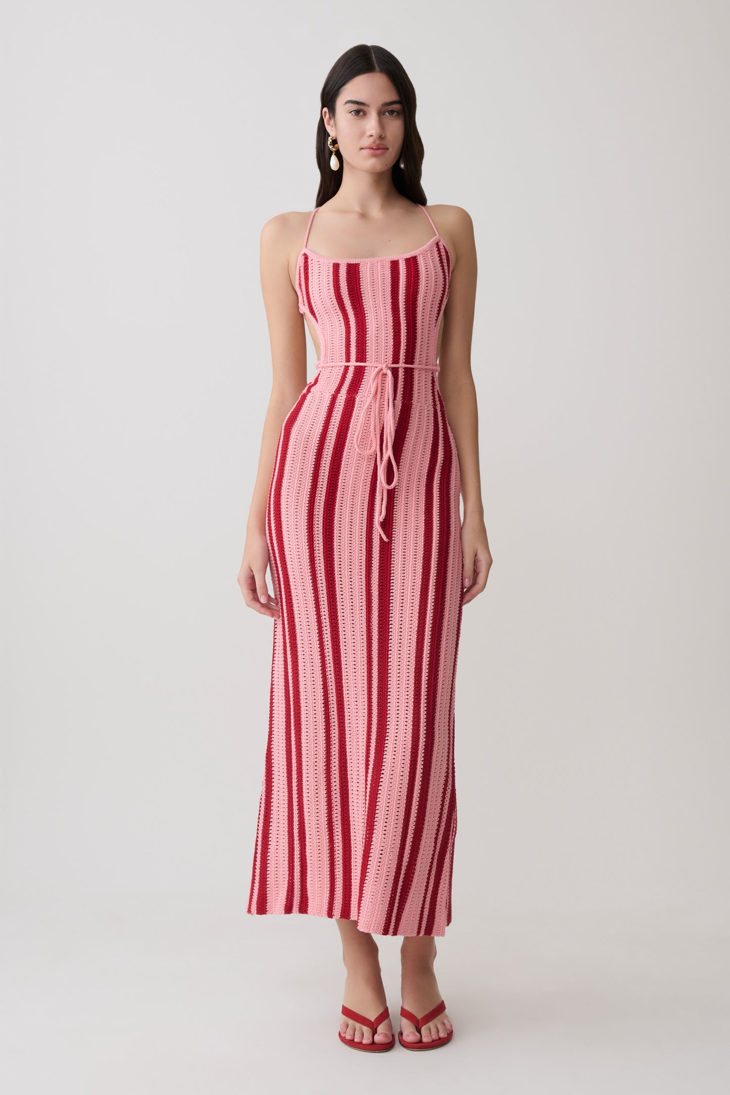 Woman wearing a pink and red striped crochet halter maxi dress.
