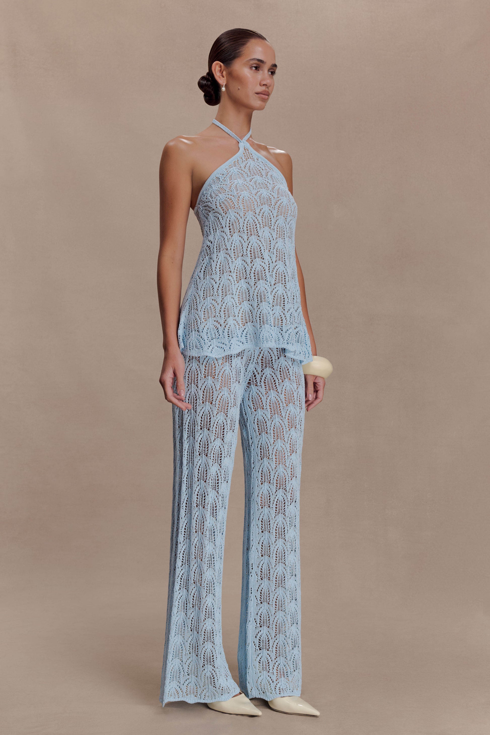 Woman wearing a light blue crochet halter top.