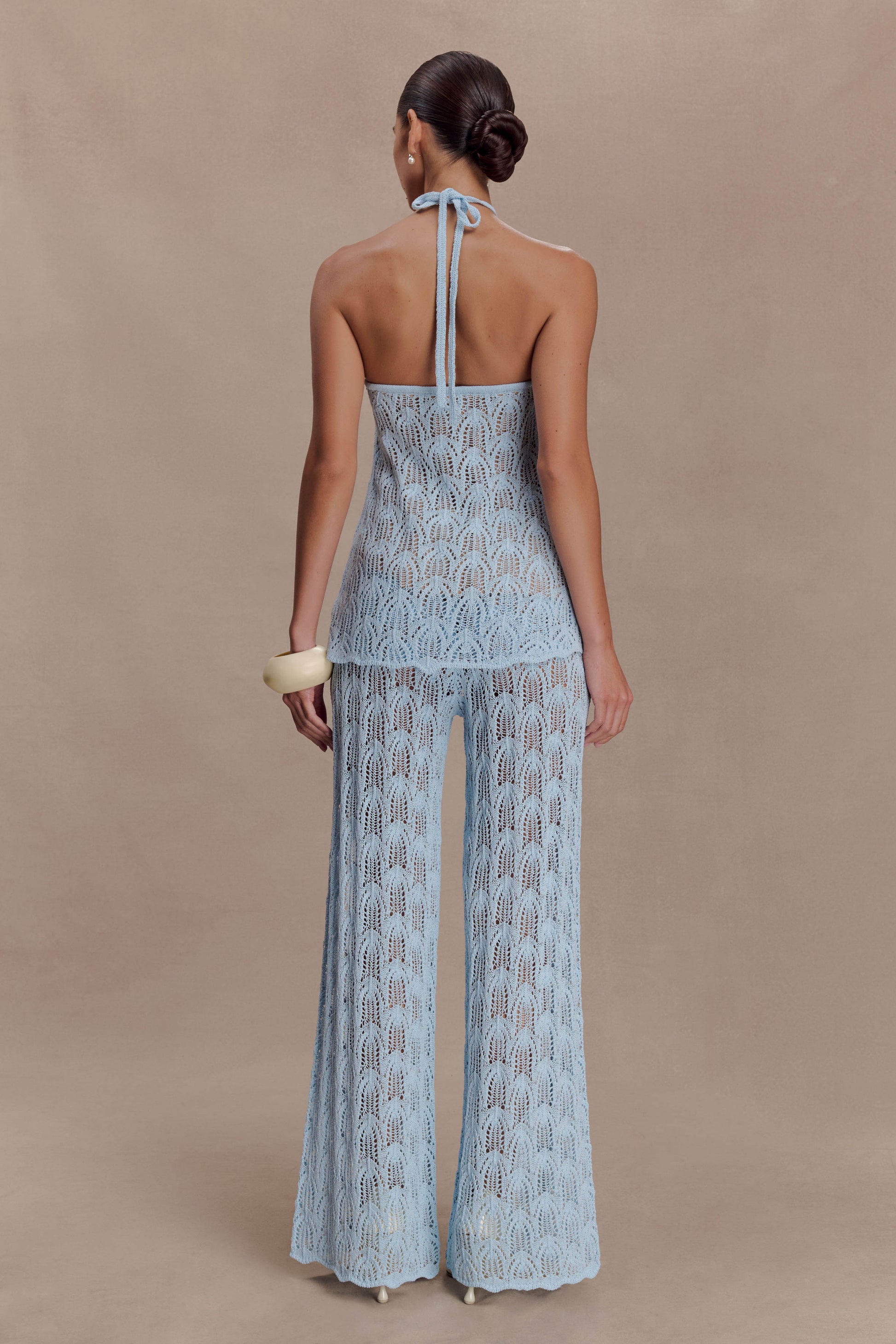 Woman wearing a light blue crochet halter top.