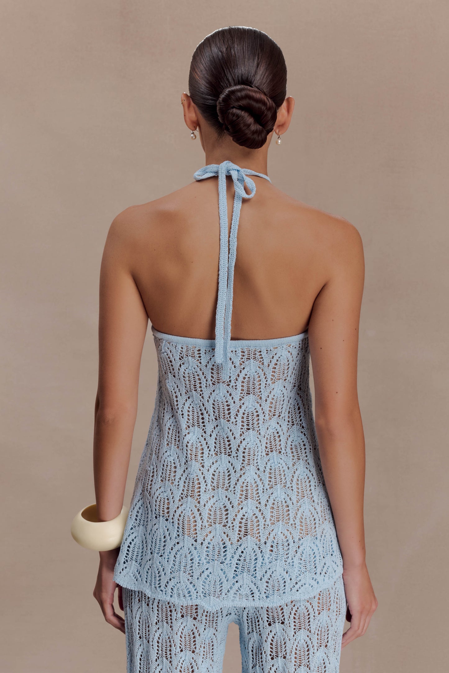 Woman wearing a light blue crochet halter top.