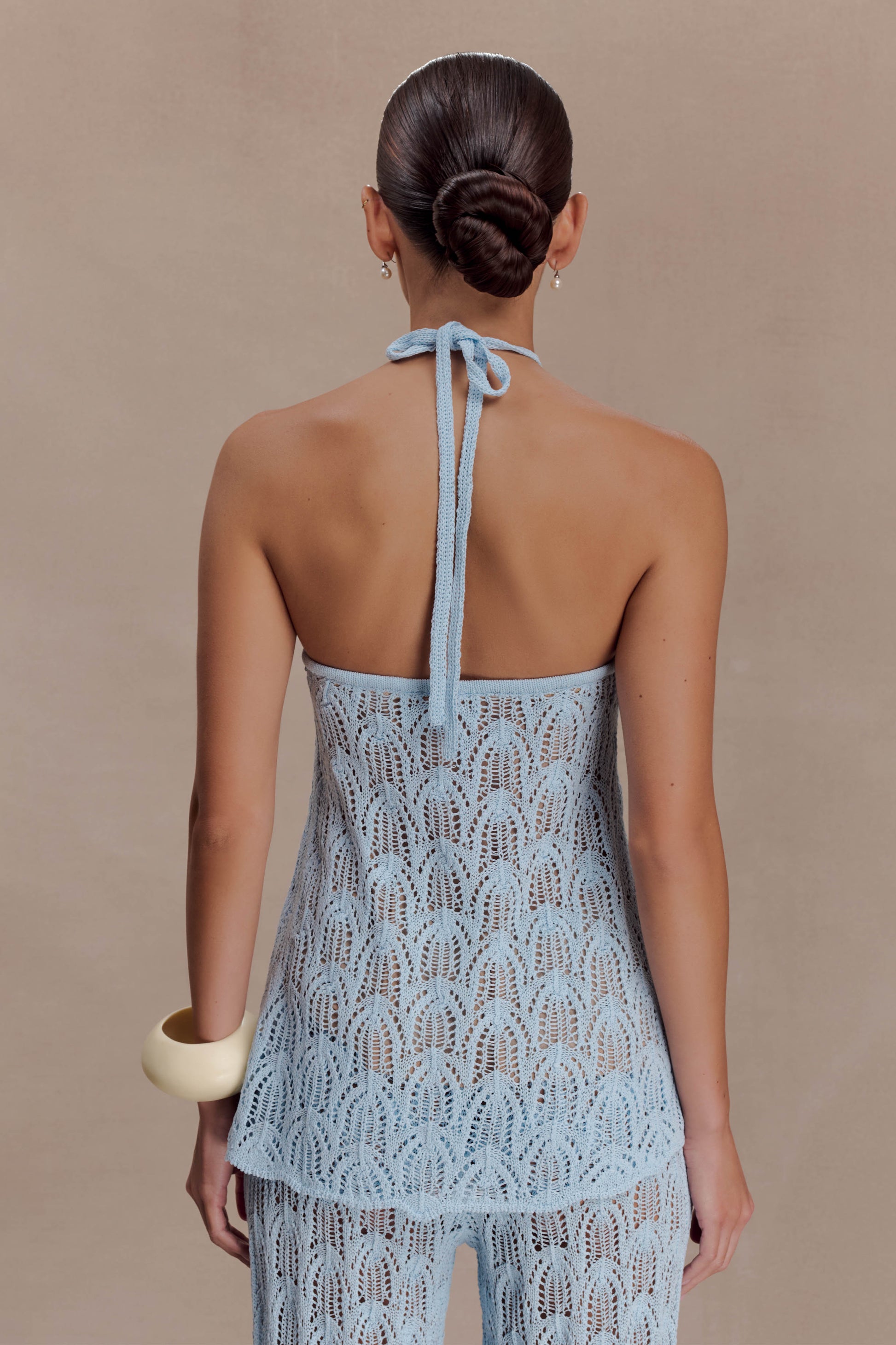 Woman wearing a light blue crochet halter top.