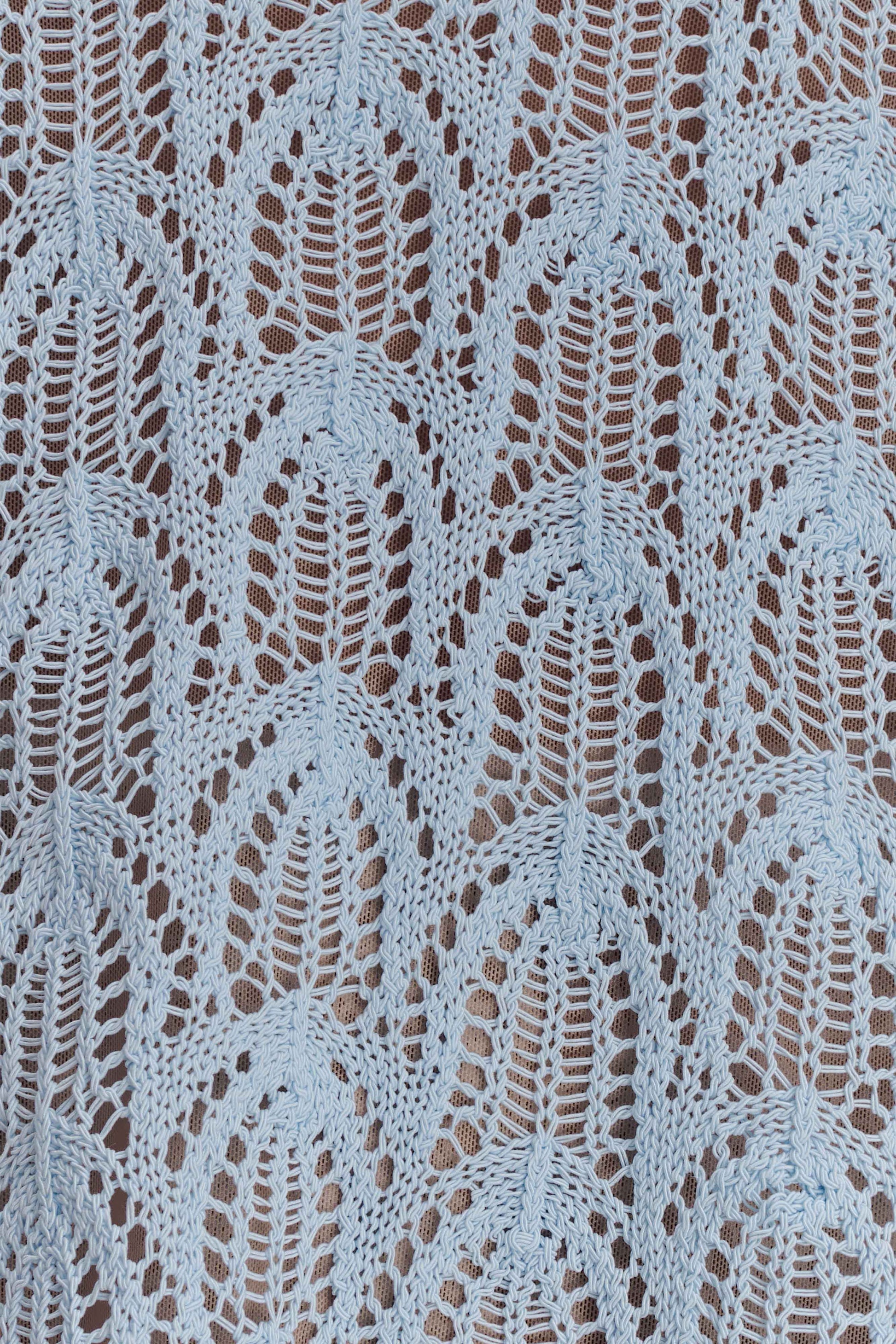 Close-up of a textured light blue crochet fabric.