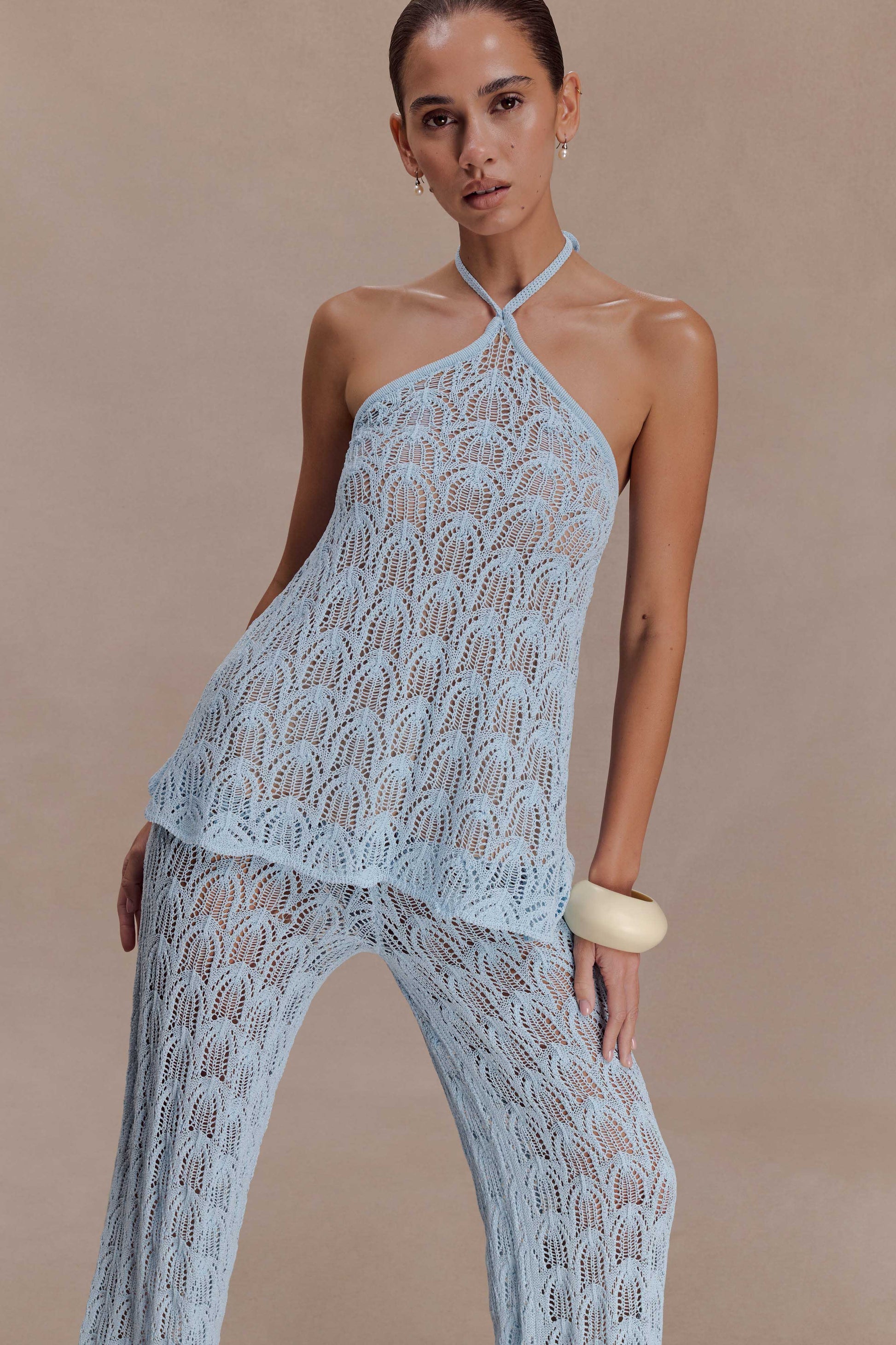 Woman wearing a light blue crochet halter top.