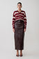 Woman wearing a striped sweater and leather skirt on a white background.