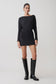 Woman wearing a black dress and knee-high boots on a white background.