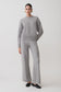 Person wearing a gray sweater and pants on a white background.