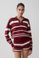 Woman wearing a maroon and white striped outfit on a plain background.