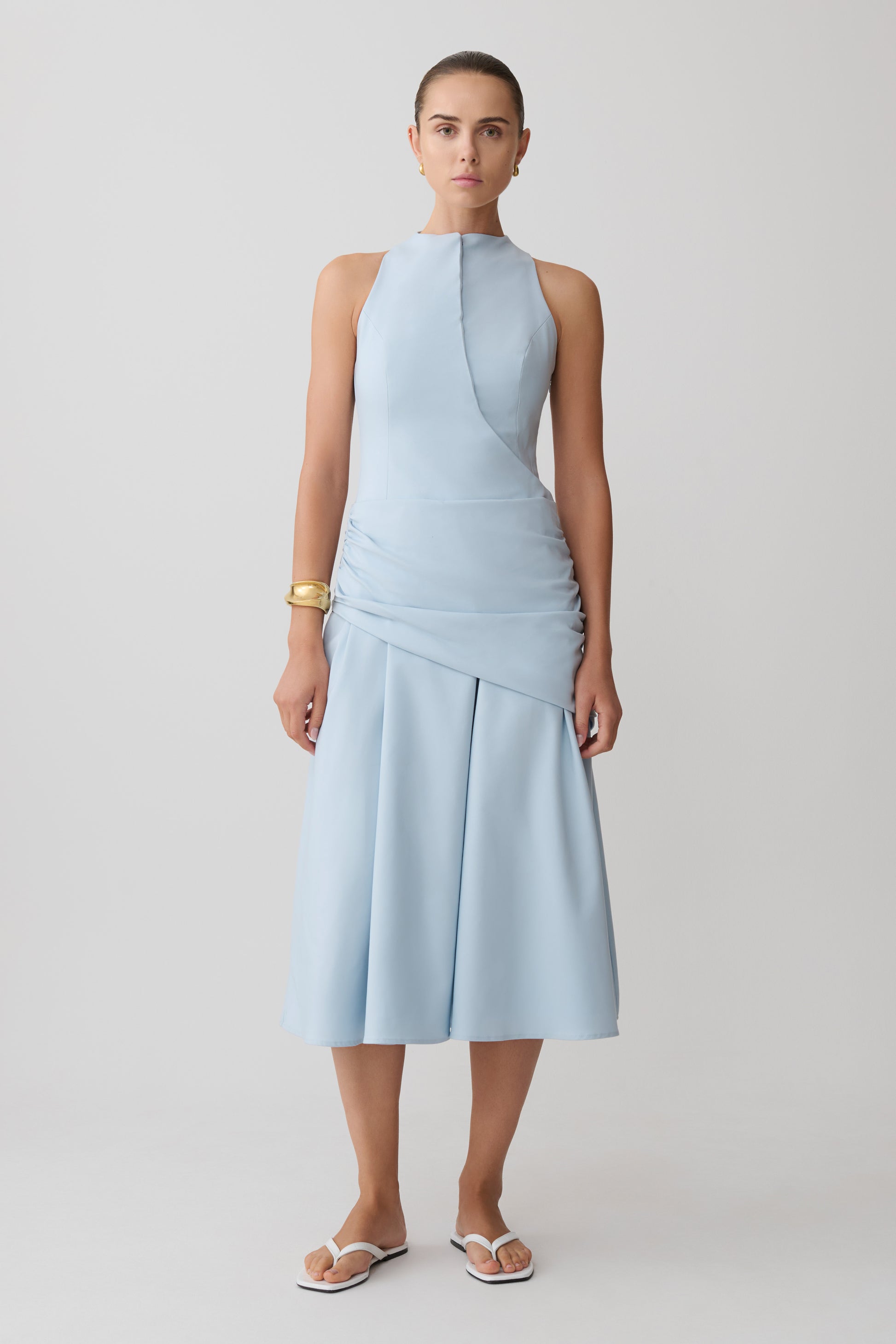 Woman wearing a light blue wrapped waist midi dress.