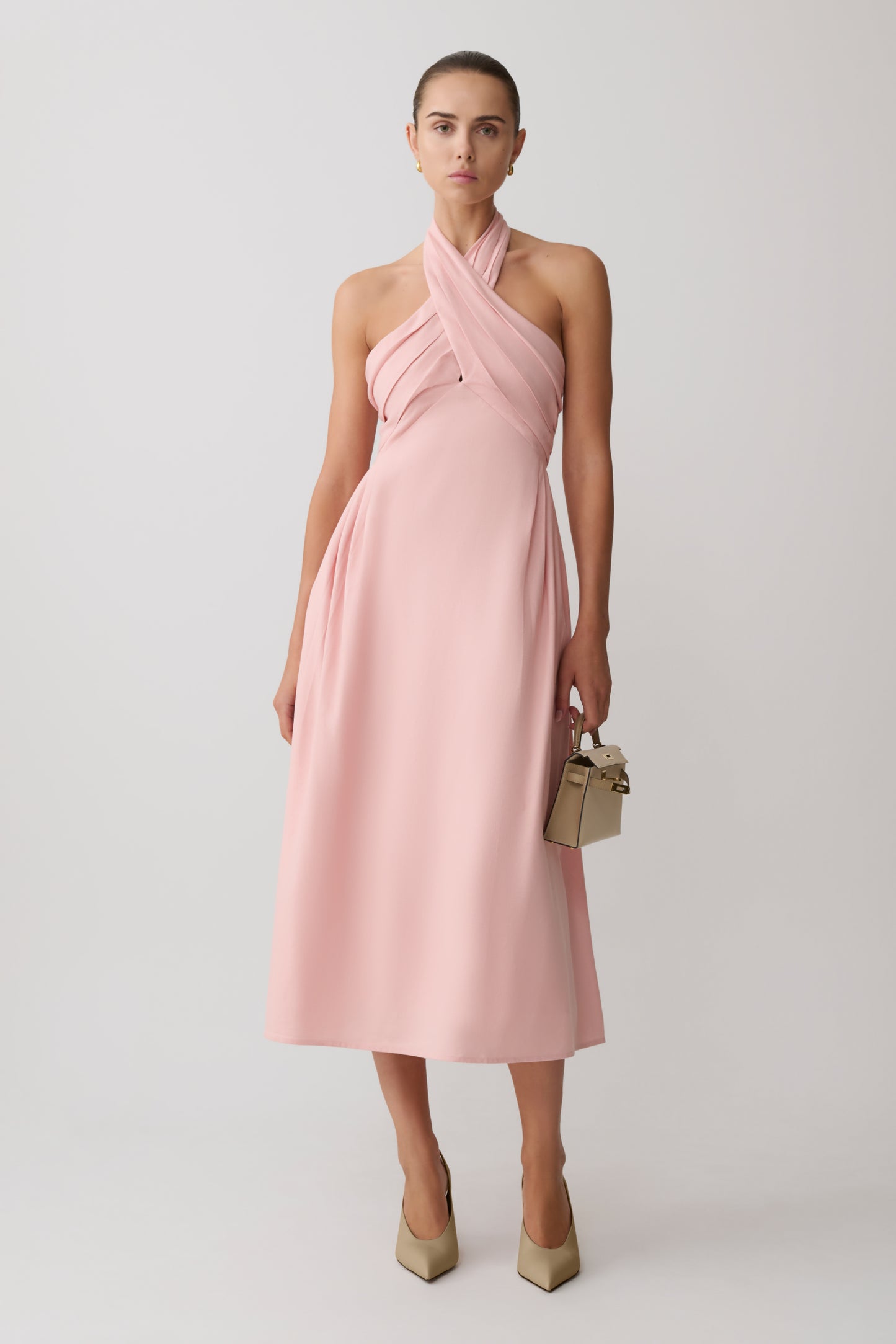 Woman wearing a pink croos over hallter maxi dress.