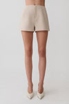 Woman wearing beige suiting shorts.