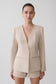 Woman wearing a beige blazer and matching shorts.