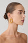 Woman wearing round gold studded earrings.