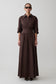 Woman wearing a long brown dress with a belt on a white background