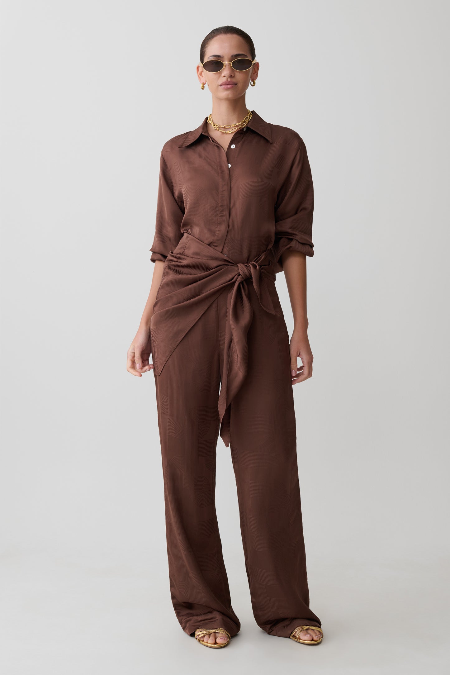 Woman wearing a brown jumpsuit on a white background