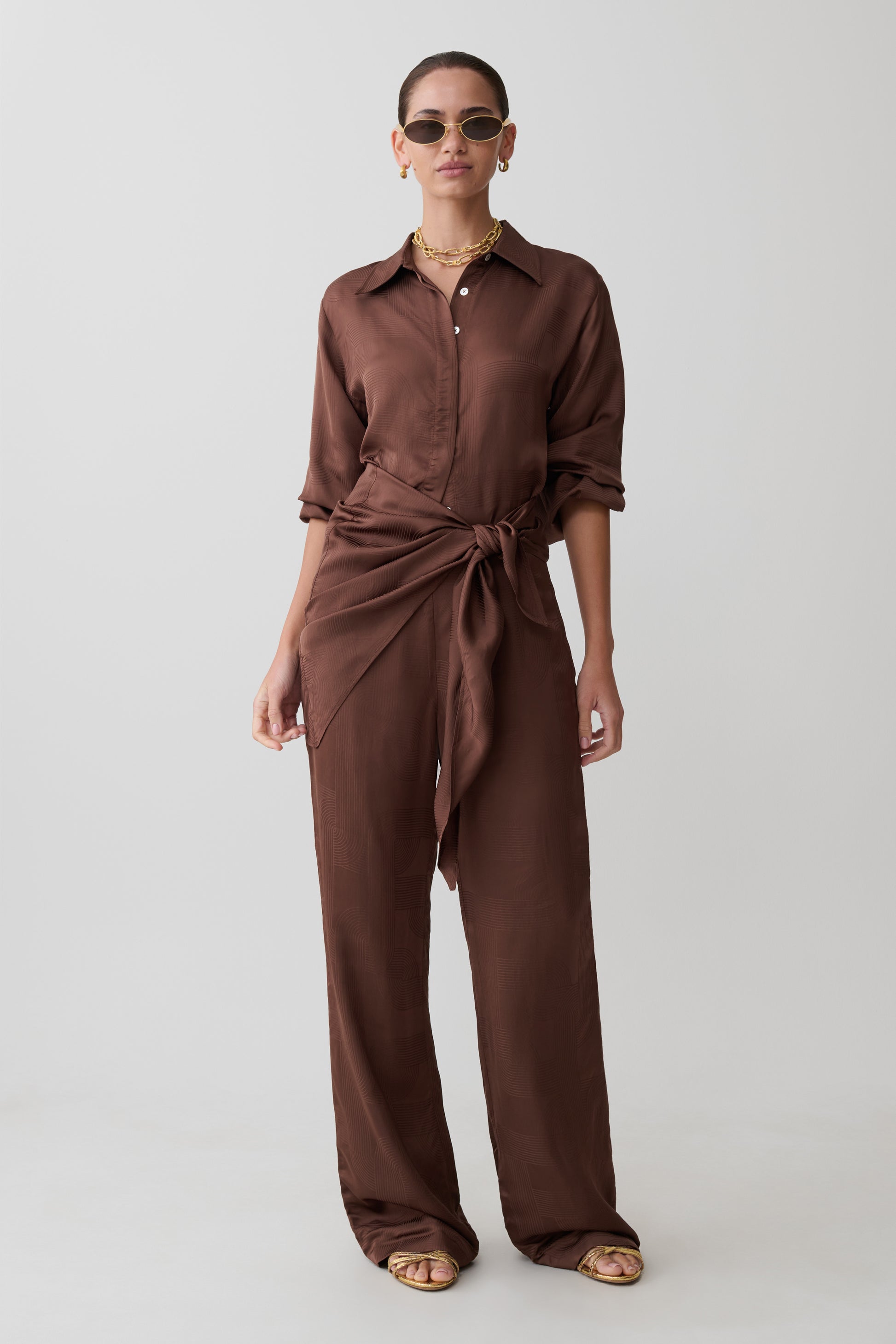 Woman wearing a brown jumpsuit on a white background